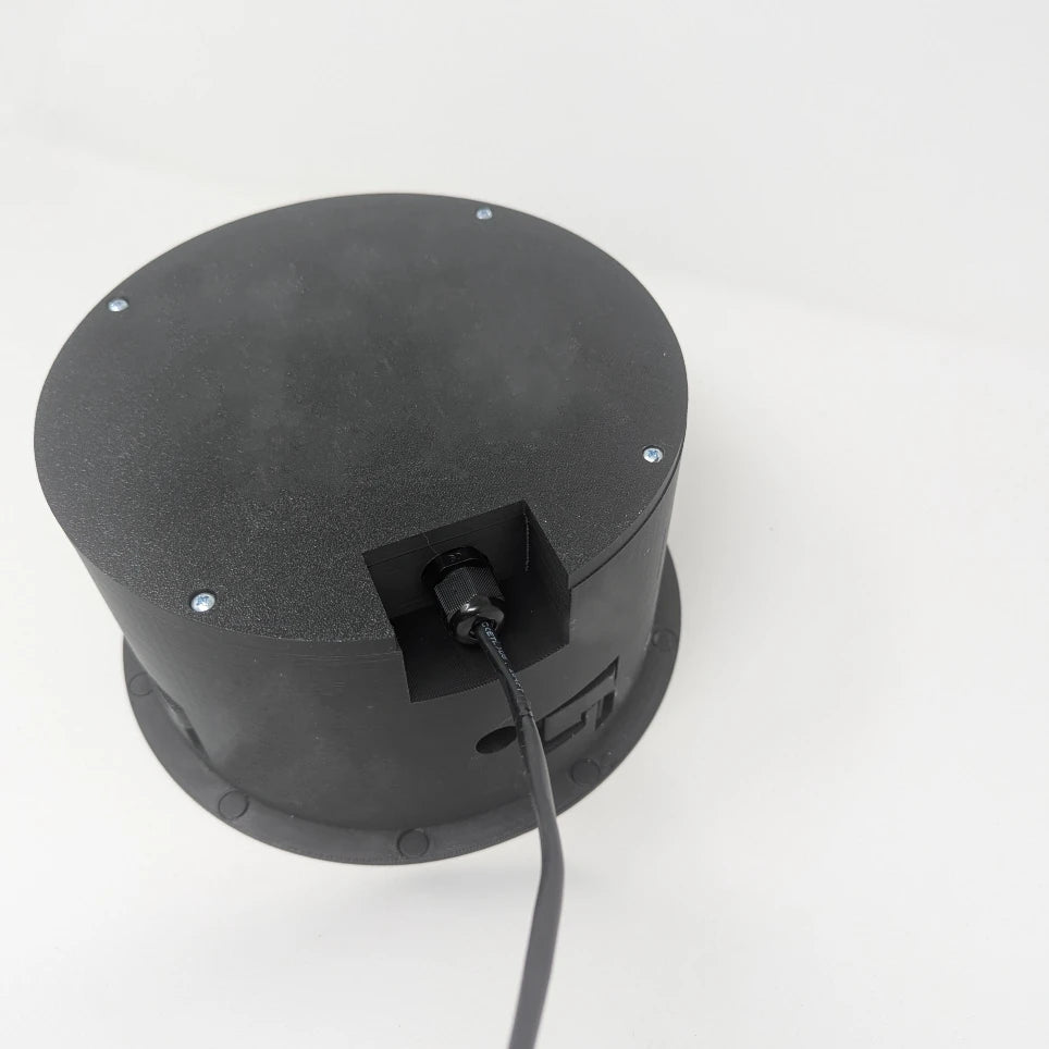 Black cylindrical Terrapin SpkrShell Architectural CW1-X4r In-Ceiling/Wall Enclosure for L-Acoustic™ X4 Speaker with a cable exiting from a recessed port on the back.